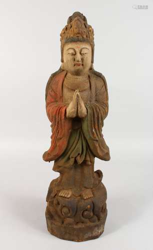 A CARVED WOOD AND PAINTED FIGURE OF A STANDING GUANYIN ON A LOTUS BASE. 23ins high.