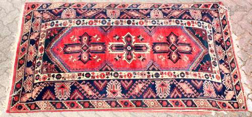A 20TH CENTURY PERSIAN CARPET, the red ground central panel with large stylised motifs within a blue