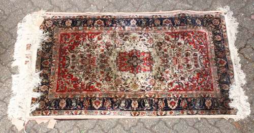A 20TH CENTURY PERSIAN PART SILK RUG, beige ground with allover floral decoration, within a