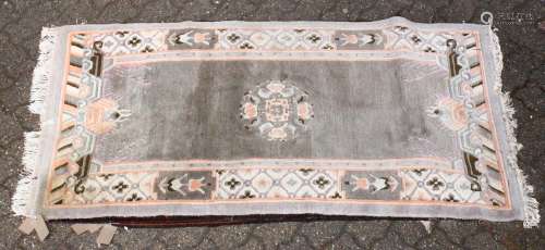 A 20TH CENTURY CHINESE RUG, grey ground with a central motif. 5ft 8ins x 2ft 10ins.