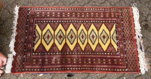 A 20TH CENTURY BOKHARA STYLE RUG, with yellow ground central panel and six lozenge shaped motifs.