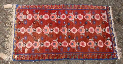 A 20TH CENTURY PERSIAN DESIGN RUG, rust ground with three rows of stylised motifs. 3ft 8ins x 2ft