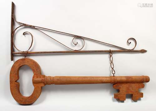 AN UNUSUAL FOLK ART/SHOP SIGN, modelled as a carved and painted wood key, suspended from a wrought