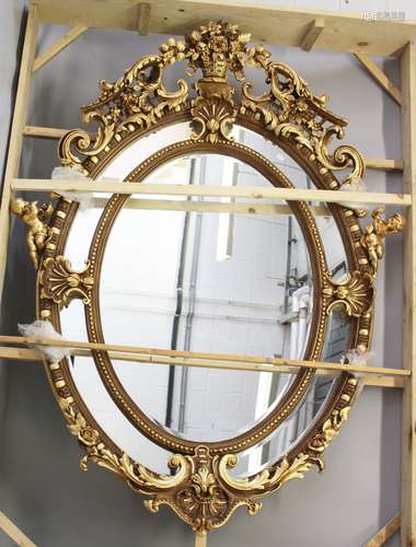 A LARGE AND IMPRESSIVE FRENCH STYLE GILT FRAMED OVAL WALL MIRROR, with highly ornate frame. 7ft 4ins