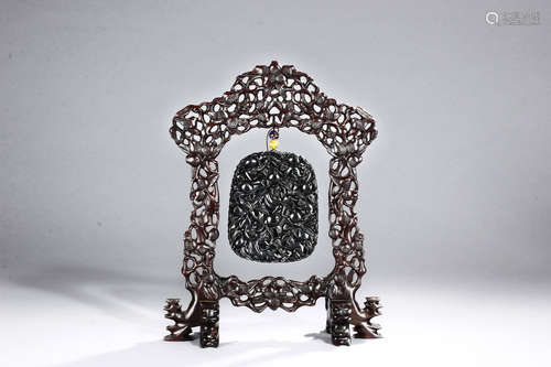 A BLACK JADE CARVED HANGING PLAQUE WITH CARVED WOODEN FRAME