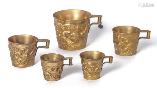 Cinq tasses en métal doré: - quatre tasses en métal doré ou jaune repoussé à [...]