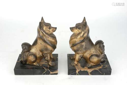 A pair of Art Deco gilded spelter dogs, early 20th century, modelled seated, on rectangular black