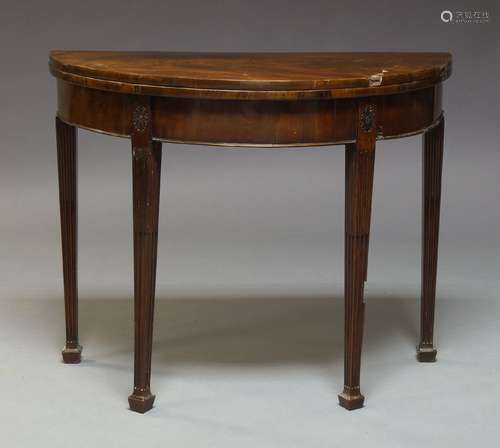 A George III mahogany card table, the semi-circular fold-over top and moulded frieze on stop