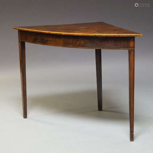 A George III mahogany bow fronted corner table, the top with a boxwood strung edge above a chequer