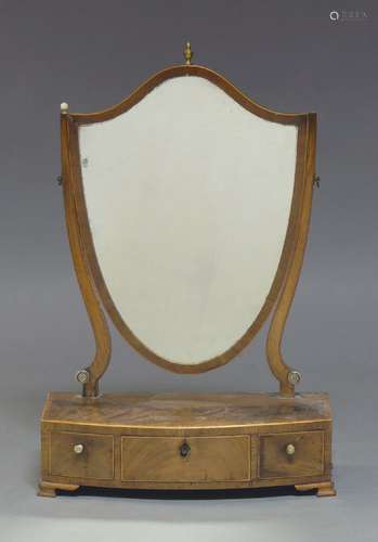 A George III mahogany and boxwood strung toilet mirror, the shield shaped plate above a three drawer