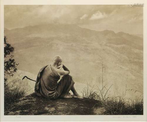 A black and white photograph of a monk looking outward to a landscape, indistinctly signed to