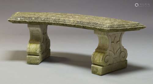 A composite stone bench, late 20th Century, with curved seat on two scrolling pedestal bases, 45cm