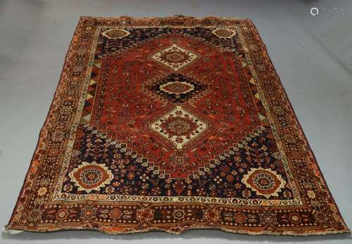 A Qashqai carpet, late 20th Century, with three medallions in a deep red field, with fire head