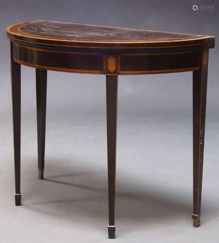 A George III mahogany and boxwood strung card table, the fold over demi-lune top enclosing claret