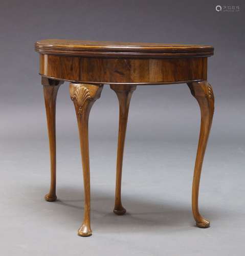 A Queen Anne style figured walnut demi-lune card table, first quarter 20th Century, the fold over