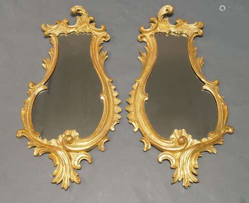 A pair of Rococo style gilt wall mirrors, early 20th Century, with scrolling border, each 101cm