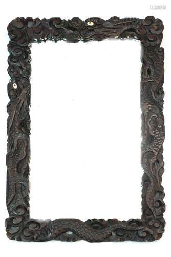 Two Chinese hardwood mirrors carved with the forms of dragon heads and scrolling decorative designs,