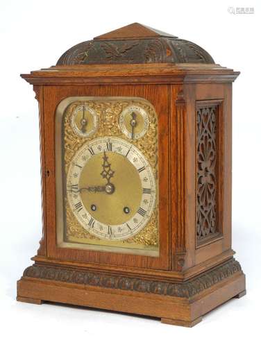 An Edwardian carved oak mantle clock, with domed and pyramid form top applied with foliate