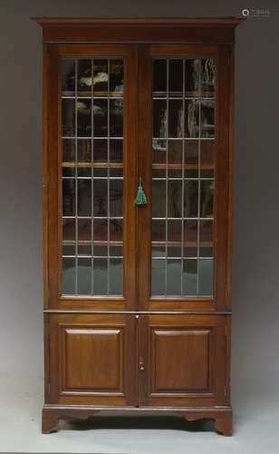 A mahogany bookcase, early 20th Century, the moulded cornice, above two glazed and leaded doors,