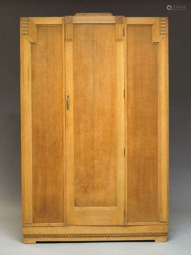 An Art Deco oak wardrobe, with floral and geometric moulding to top, having central cupboard door