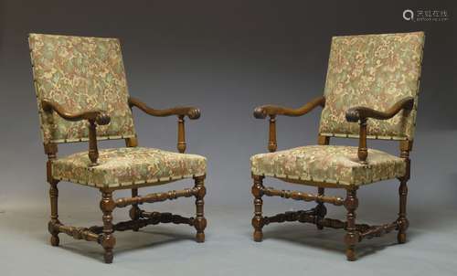 A pair of Flemish style walnut armchairs, 20th Century, the padded oblong backs above stuffed seats,