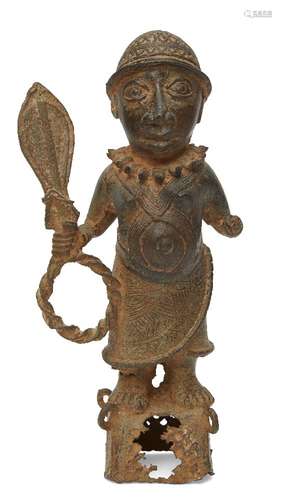 A Benin style bronze figure of a Chieftain, modelled standing holding a ceremonial paddle and quoit,