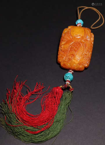 AN AMBER CARVED CARNE PATTERN PENDANT