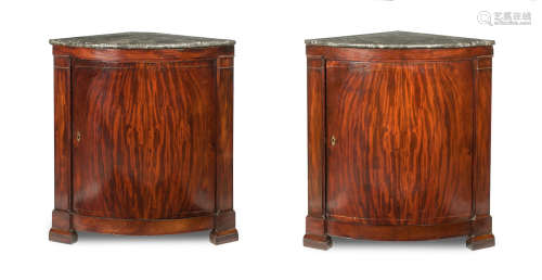 A pair of early 19th century German figured mahogany bowfronted marble top corner cabinets