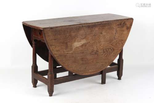 Property of a lady - an early 18th century oak oval topped gate-leg dining table, with end drawer,