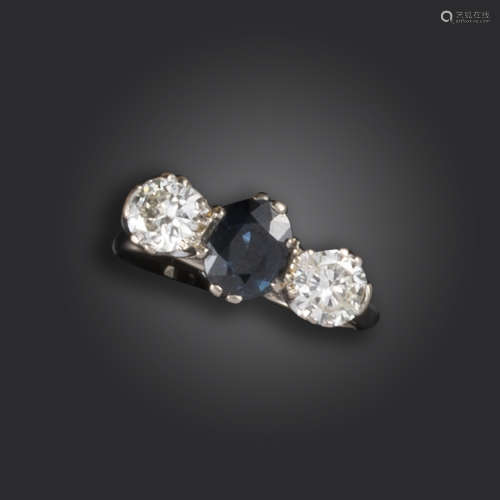 A sapphire and diamond three-stone ring, set with an oval-shaped sapphire between brilliant-cut