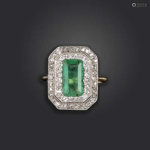 An Edwardian emerald and diamond ring, set with an emerald-cut emerald within two borders of rose-