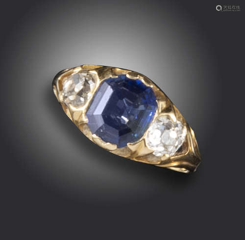 An early 20th century sapphire and diamond three-stone ring, the emerald-cut sapphire flanked with