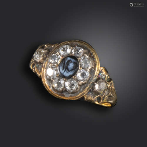 A Victorian onyx and diamond mourning ring, the oval onyx cameo set within a surround of old