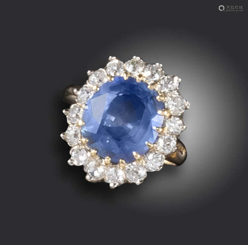 A sapphire and diamond cluster ring, the cushion-shaped sapphire is set within a surround of round