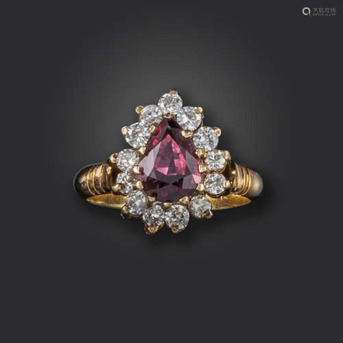 A ruby and diamond cluster ring, the pear-shaped ruby set within a surround of round brilliant-cut