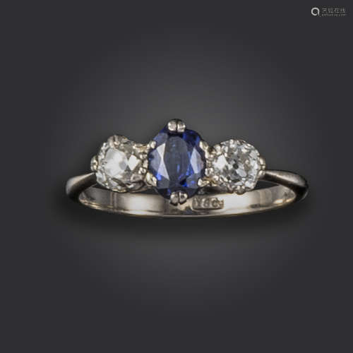 A sapphire and diamond three-stone ring, set with an oval-shaped sapphire between old cushion-shaped