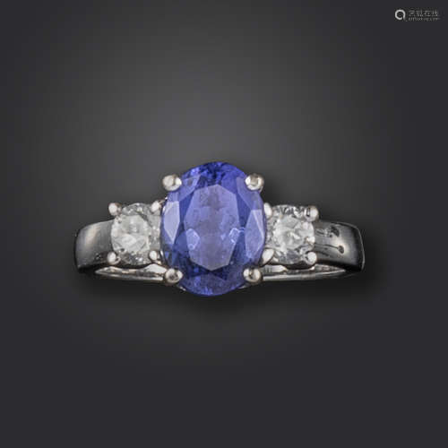 A tanzanite and diamond three-stone ring, the oval-shaped tanzanite set with two round brilliant-cut