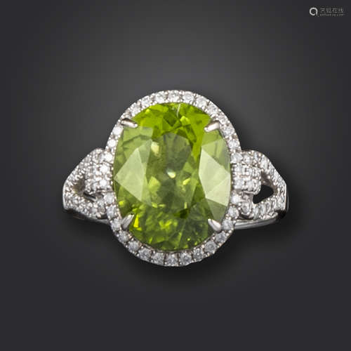 A peridot and diamond cluster ring, set with an oval-shaped peridot within a surround of circular-