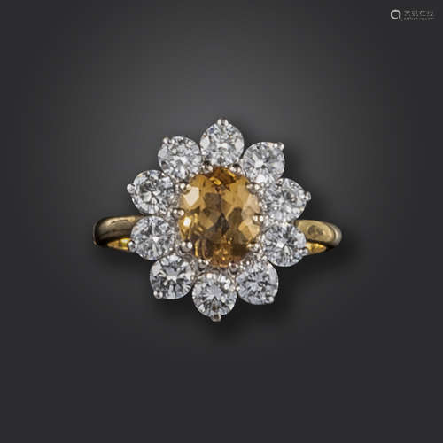 A topaz and diamond cluster ring, the oval-shaped orange topaz set within a surround of round