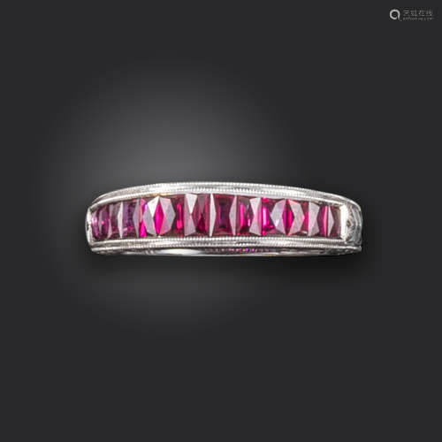 A ruby half-hoop ring, channel-set with French-cut rubies, with engraved decoration to the shoulders