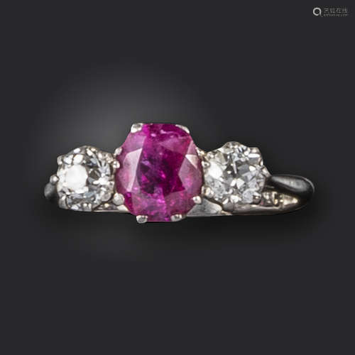 A ruby and diamond three-stone ring, set with a cushion-shaped ruby between old circular-cut