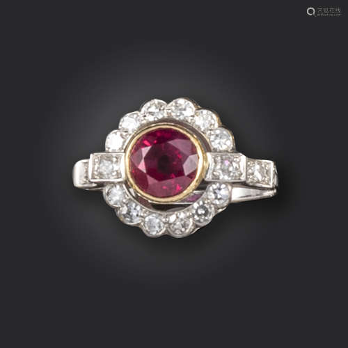 A ruby and diamond cluster ring, set with a circular-cut ruby within a surround of single-cut