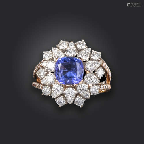 A tanzanite and diamond cluster ring, centred with a cushion-shaped tanzanite weighing approximately