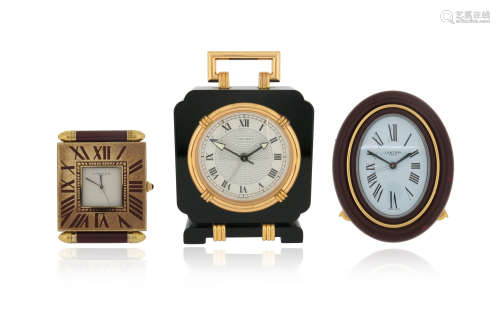 Three travel clocks by Cartier, including a Must de Cartier brass and red enamel travel alarm clock,