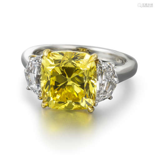 A fancy vivid yellow and white diamond three-stone ring, the cushion-shaped diamond weighs 5.