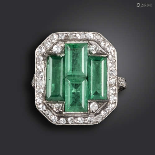 An Art Deco emerald and diamond ring, the four emerald-cut emeralds set within a surround of