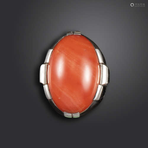 λ A French Art Deco coral-mounted silver ring, the oval-shaped coral cabochon is set in a raised
