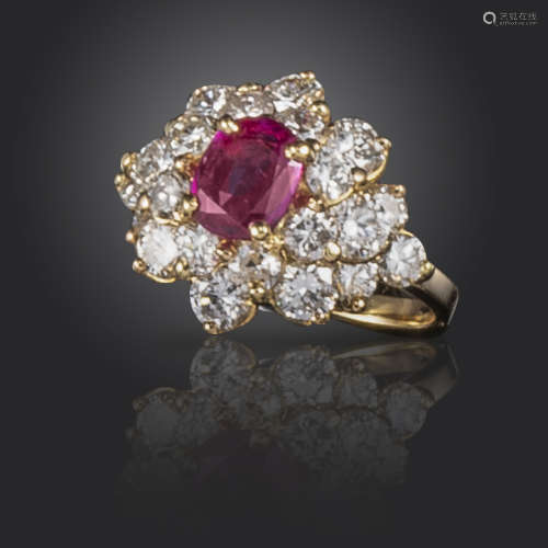 A ruby and diamond cluster ring, of flowerhead design, centred with an oval-shaped ruby within a