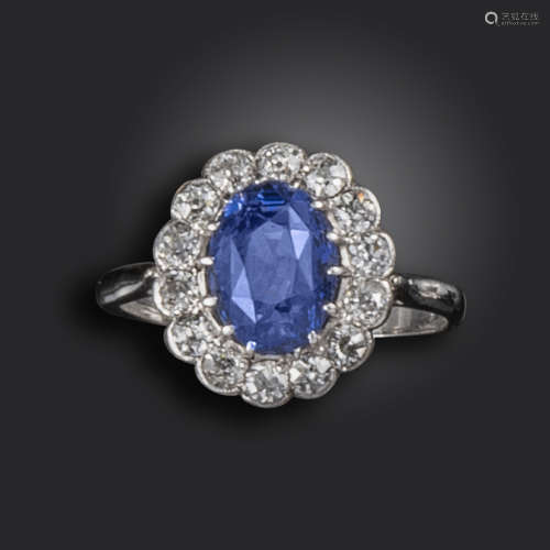 A sapphire and diamond cluster ring, set with an oval-shaped sapphire within a surround of old
