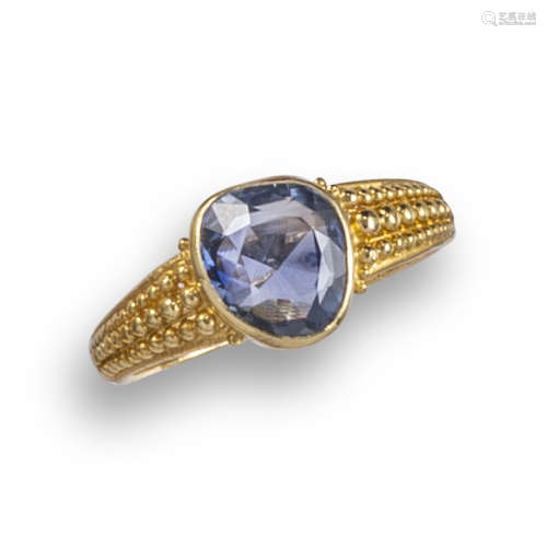A sapphire-set gold ring, rubover set with an asymmetrical oval-shaped sapphire, with pellet